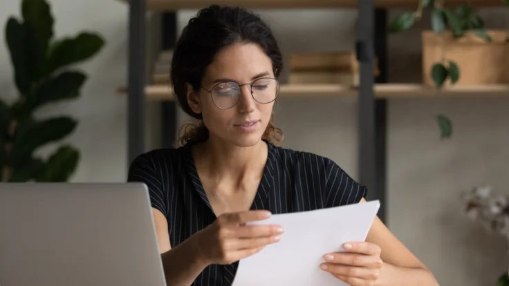 Deckblatt Bewerbung: Bewerberin prüft Unterlagen an ihrem Schreibtisch vor dem Vorstellungsgespräch.