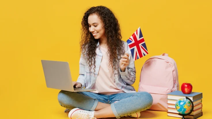 Bewerbung auf Englisch: Junge Frau bereitet mit einem Laptop und einer britischen Flagge ihre Bewerbung für internationale Jobs vor.